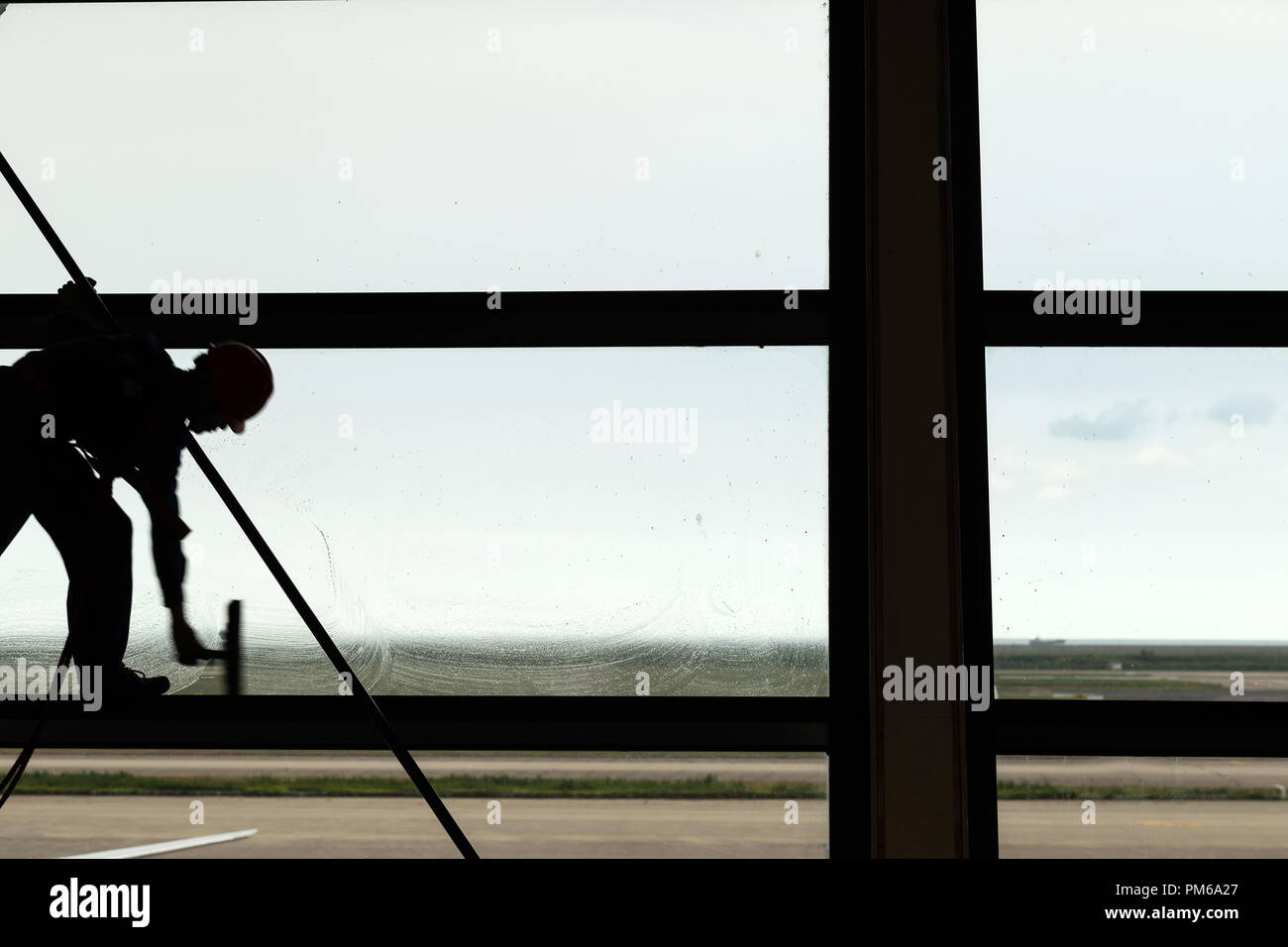 Silhouette colpo di pulizia del vetro da spiderman lavoratore in aeroporto. Foto Stock