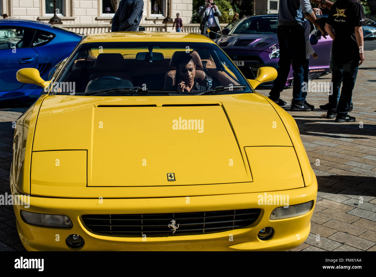 Una donna si vede all interno di un giallo Ferrari durante lo spettacolo. Piccadilly boys, la super car racer club di sviluppo Kream sfilate le loro auto personalizzate in Kream Liberty a piedi M3 Edizione a Waterloo Place a Londra. Foto Stock