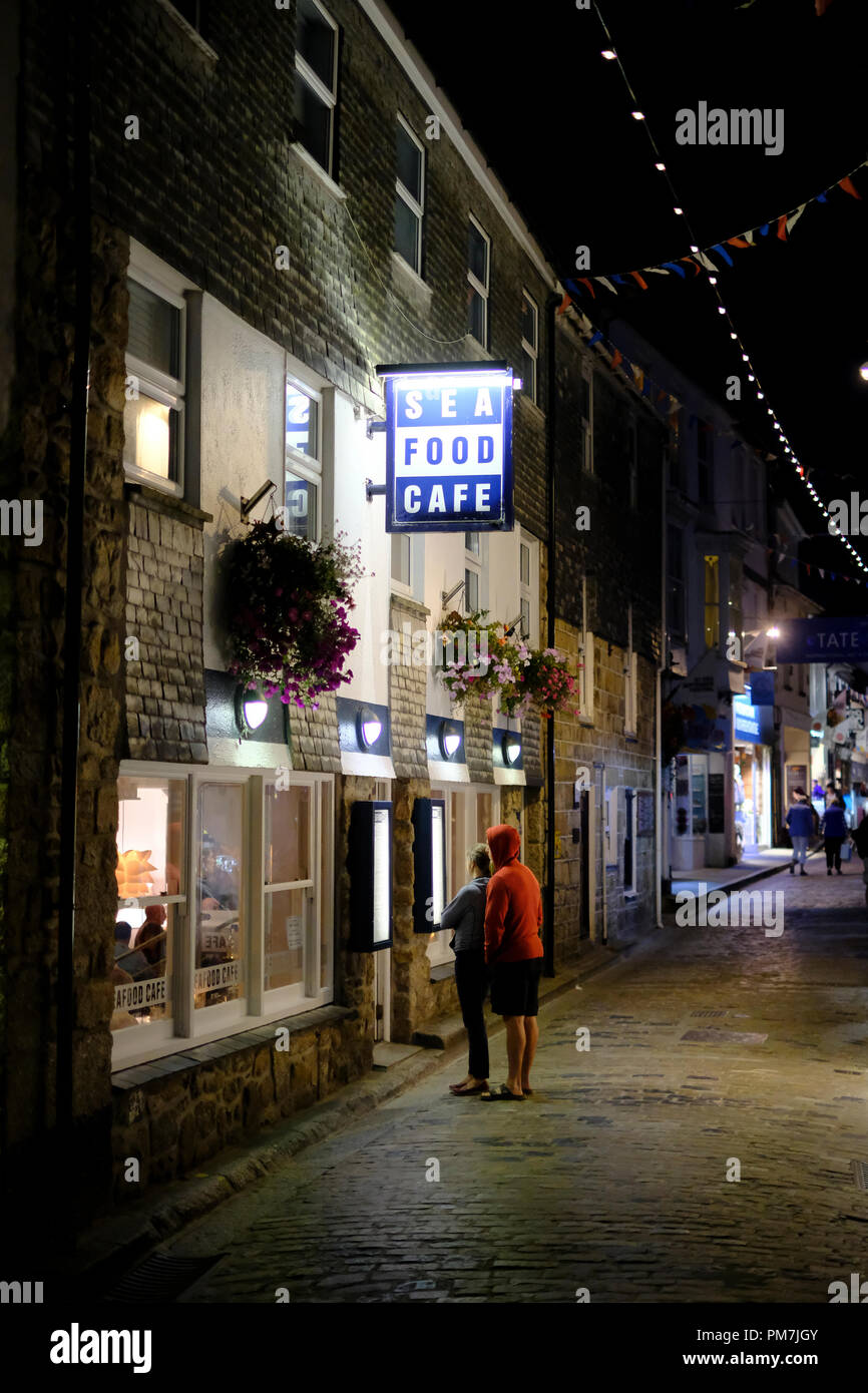 Un giovane guardando il menù al Sea Food Cafe su Fore Street in St Ives, Cornovaglia Foto Stock