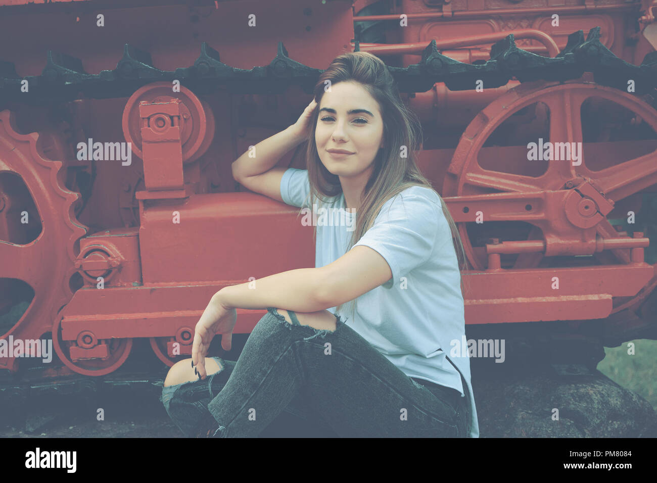 Una giovane donna elegante vestito di casual jeans strappati e camicia bianca si posa su un sfondo colorato. Visitare il vecchio museo dei trasporti. Una donna Foto Stock