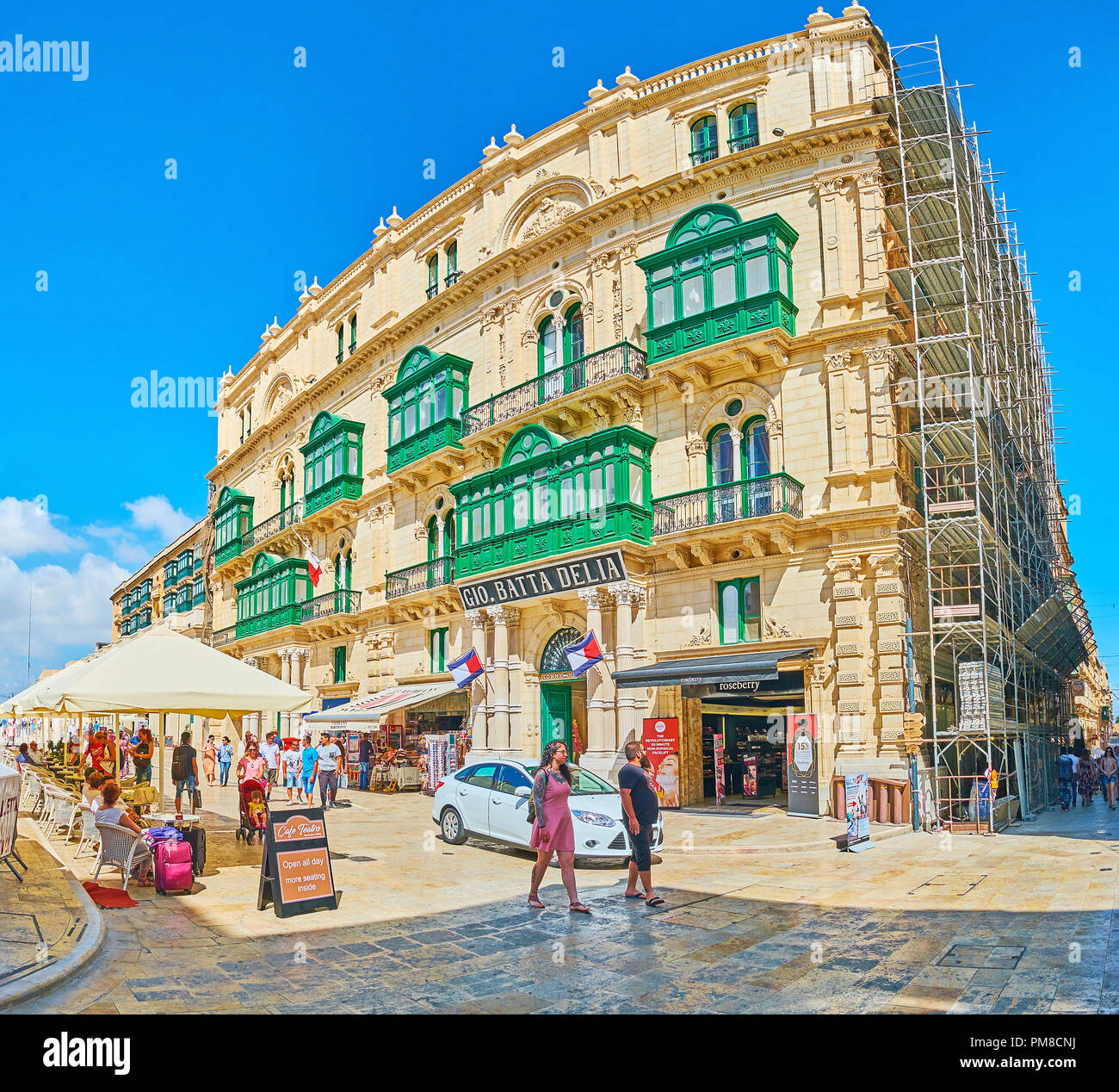 La Valletta, Malta - 17 giugno 2018: Panorama del palazzo storico in Repubblica Street con negozi e stalle al piano terra e scenic Maltese verde Foto Stock