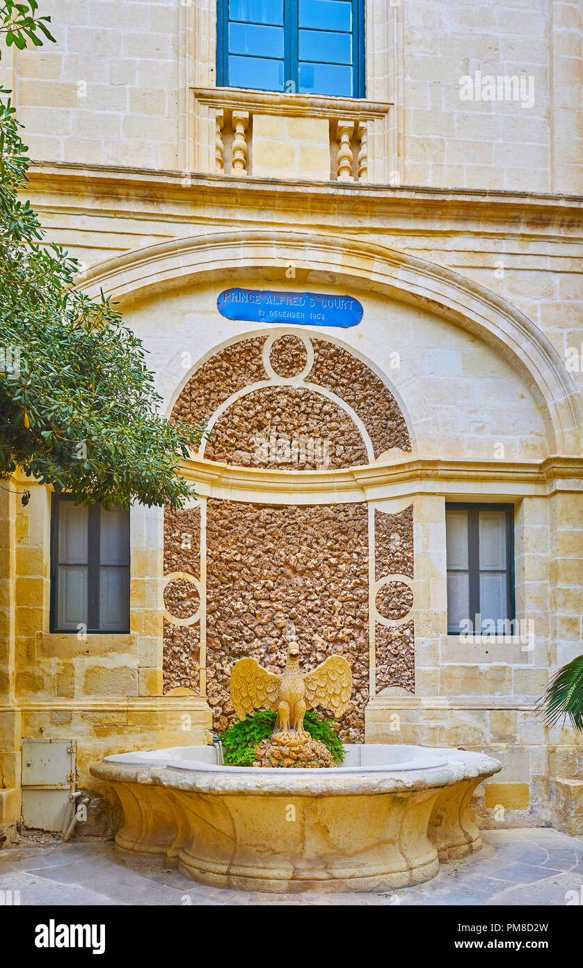 La Valletta, Malta - 17 giugno 2018: Il Prince Alfred's Courtyard di Grandmaster's Palace vanta scenic Bird Fontana, nascosto dietro gli alberi del gar Foto Stock