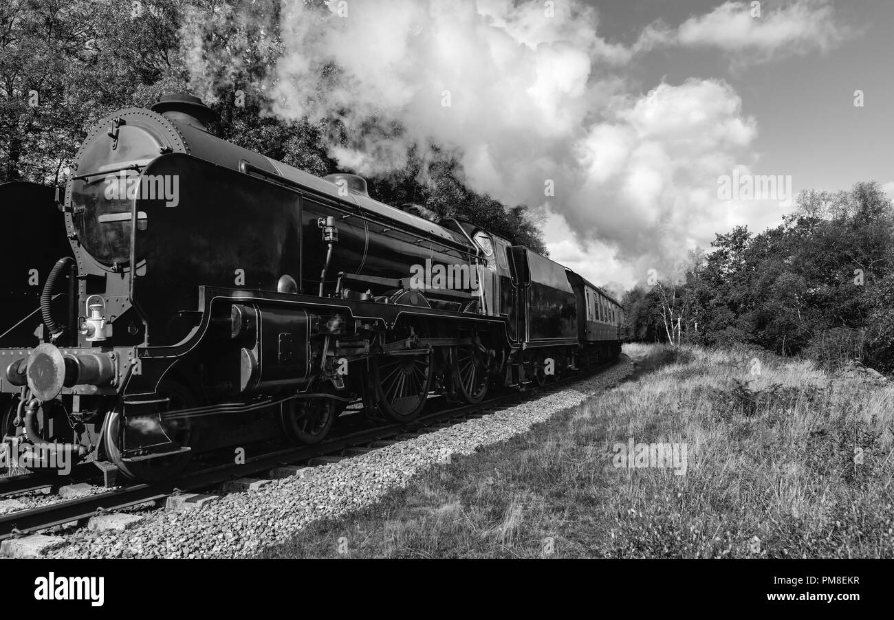 Un vintage treno a vapore aratri attraverso il North York Moors su un autunno mattina vicino a Goathland, nello Yorkshire, Regno Unito. Foto Stock