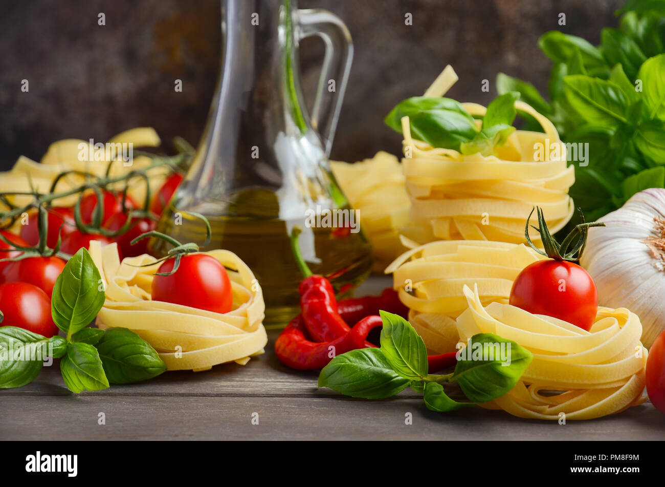 Pasta, verdure, erbe aromatiche e spezie per il cibo italiano sullo sfondo di legno, fuoco selettivo. Foto Stock