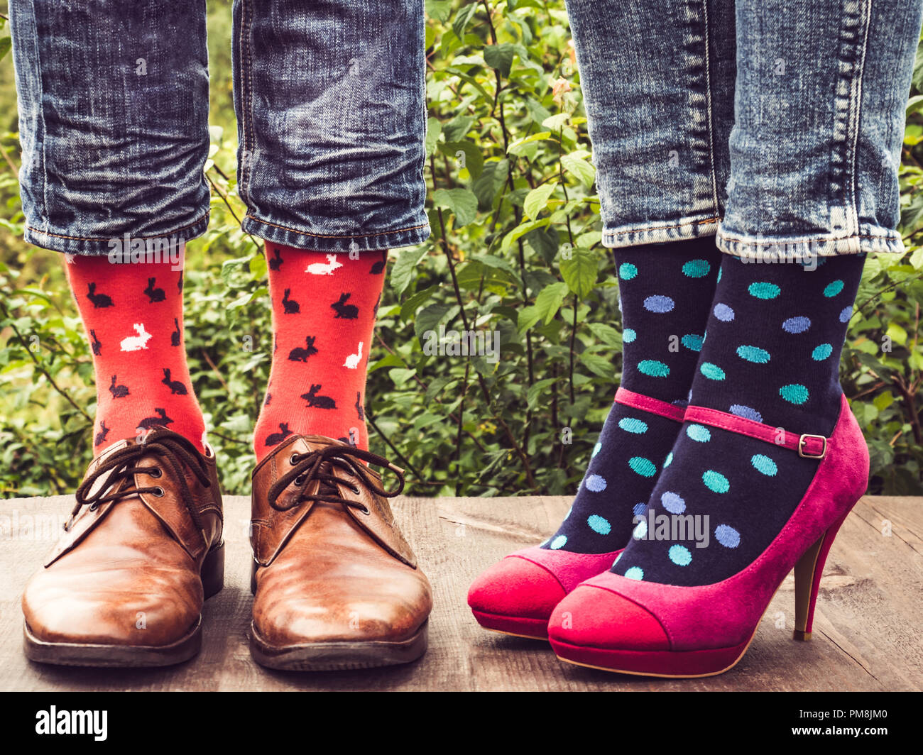 Uomini e donne i piedi nelle scarpe eleganti, luminose, calze colorate con  strisce modelli e immagini di gelato sulla terrazza in legno sul backgroun  Foto stock - Alamy