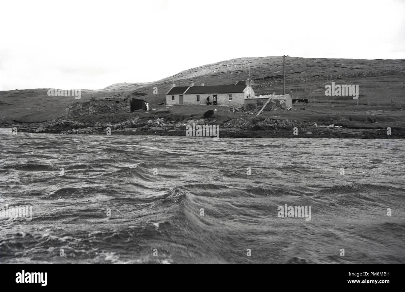 Degli anni Cinquanta, storico, un singolo-storey crofter's cottage si siede da bordo dell'acqua nel paesaggio arido di Orkney isole al largo della costa nord della Scozia. Queste isole dimenzogne sono notevoli per la loro mancanza di alberi e le forti correnti di marea in firths. Foto Stock