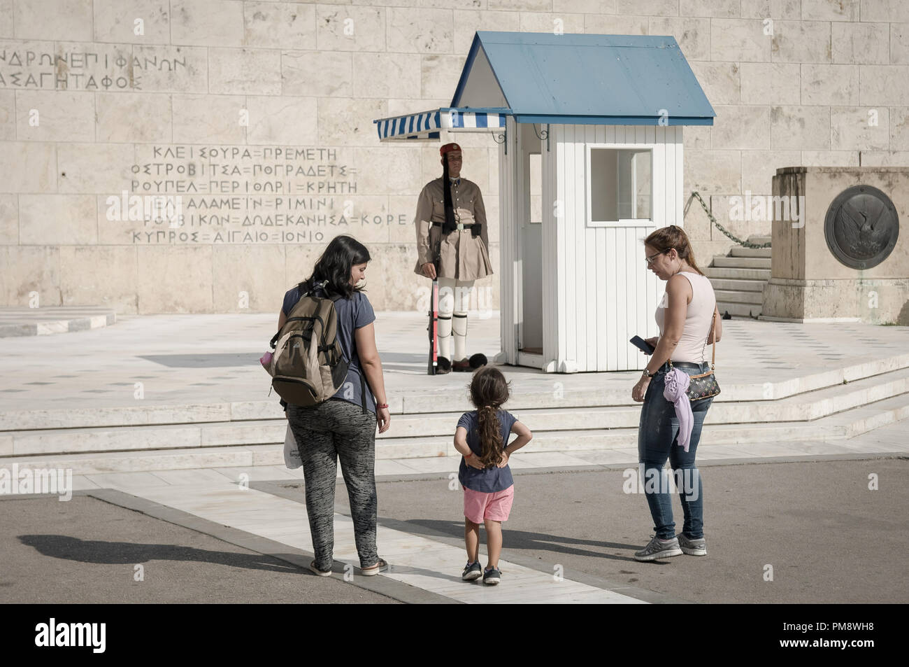 Due donne e una bambina si vede guardando il soldato sconosciuto monumento. I turisti si vede guardando il cambio della guardia a Syndagma piazza davanti al parlamento greco ad Atene, in Grecia. Foto Stock