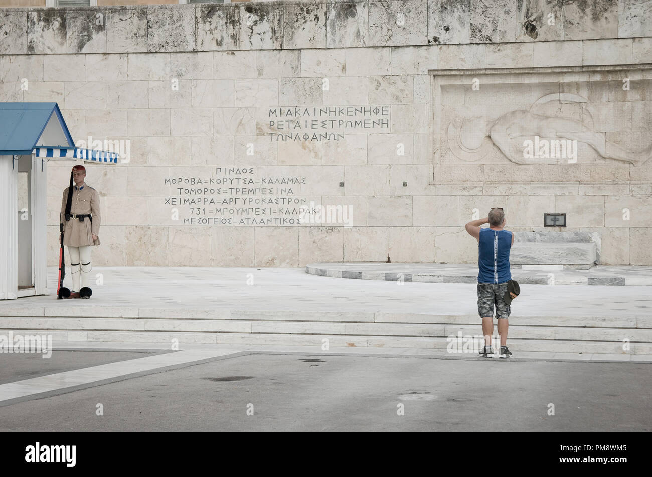 Un visto turistico di scattare una foto di un soldato sconosciuto monumento. I turisti si vede guardando il cambio della guardia a Syndagma piazza davanti al parlamento greco ad Atene, in Grecia. Foto Stock