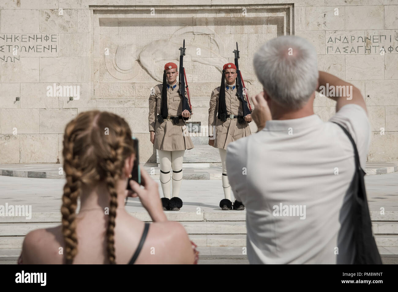 Due turisti visto scattare foto del cambio della guardia. I turisti si vede guardando il cambio della guardia a Syndagma piazza davanti al parlamento greco ad Atene, in Grecia. Foto Stock
