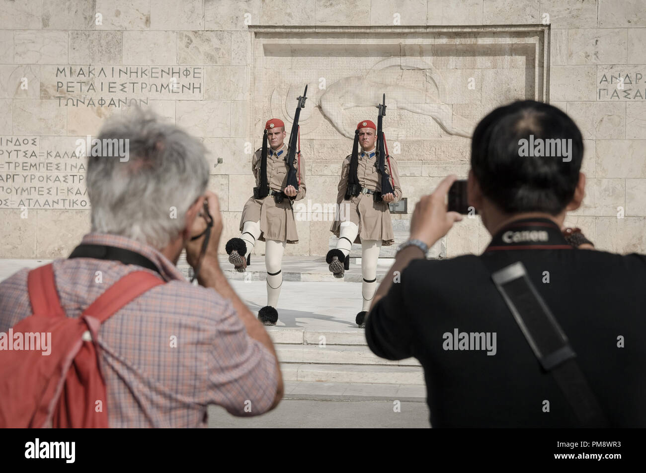 Due turisti visto scattare foto del cambio della guardia. I turisti si vede guardando il cambio della guardia a Syndagma piazza davanti al parlamento greco ad Atene, in Grecia. Foto Stock