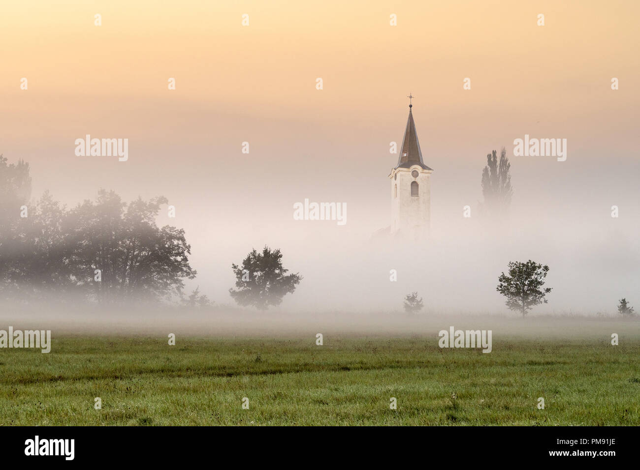 Piccola chiesa nella nebbia. Foschia mattutina dalla sunrise. Foto Stock