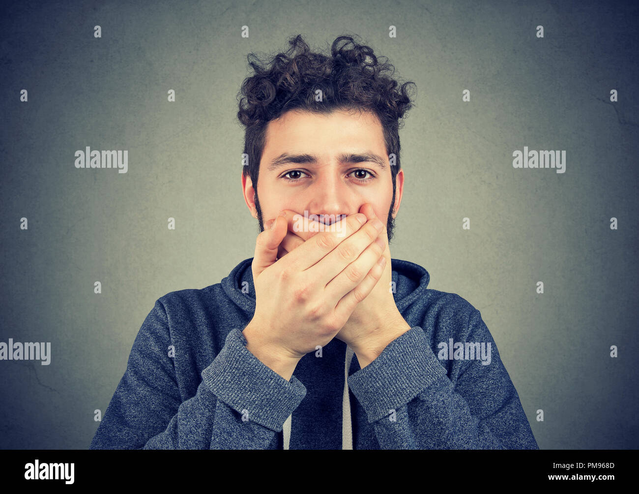 Tanga giovane uomo che copre la bocca mantenendo la privacy e non parlava male Foto Stock