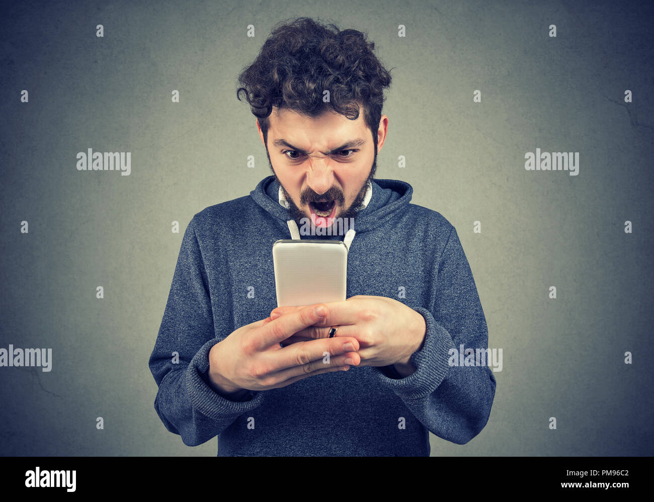 Frustrati iracondo la lettura di un messaggio di testo sul suo smartphone frustrati Foto Stock