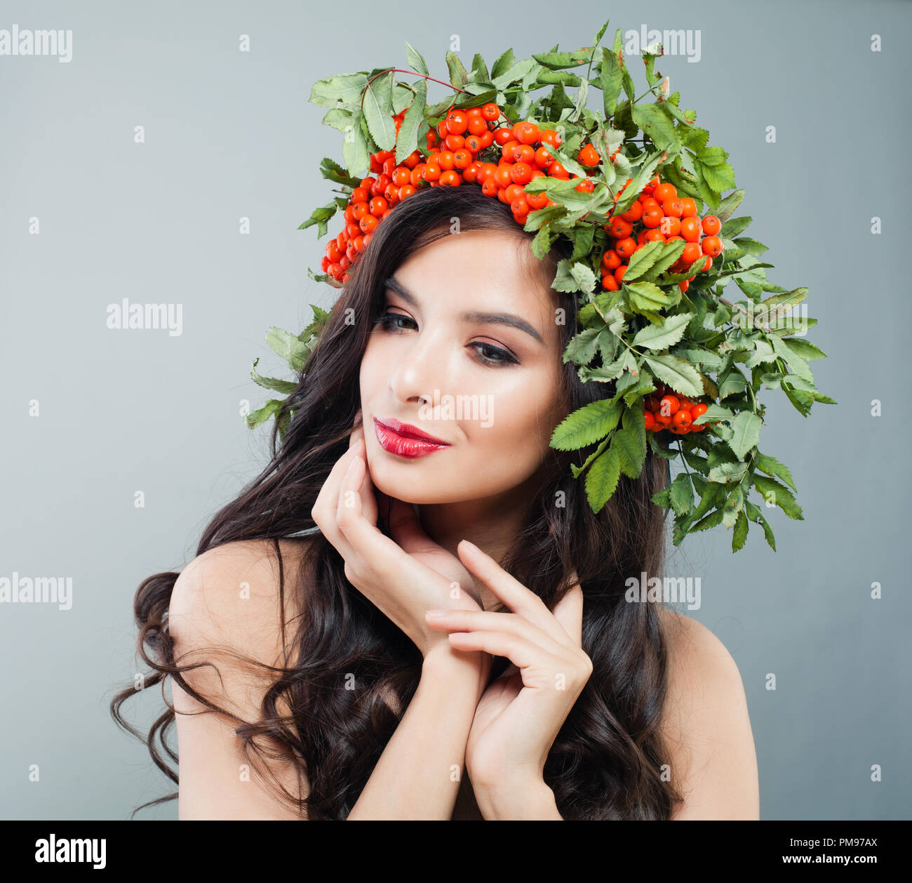 Giovane donna bruna con lunghi capelli ondulati, trucco e autunno bacche e foglie corona Foto Stock