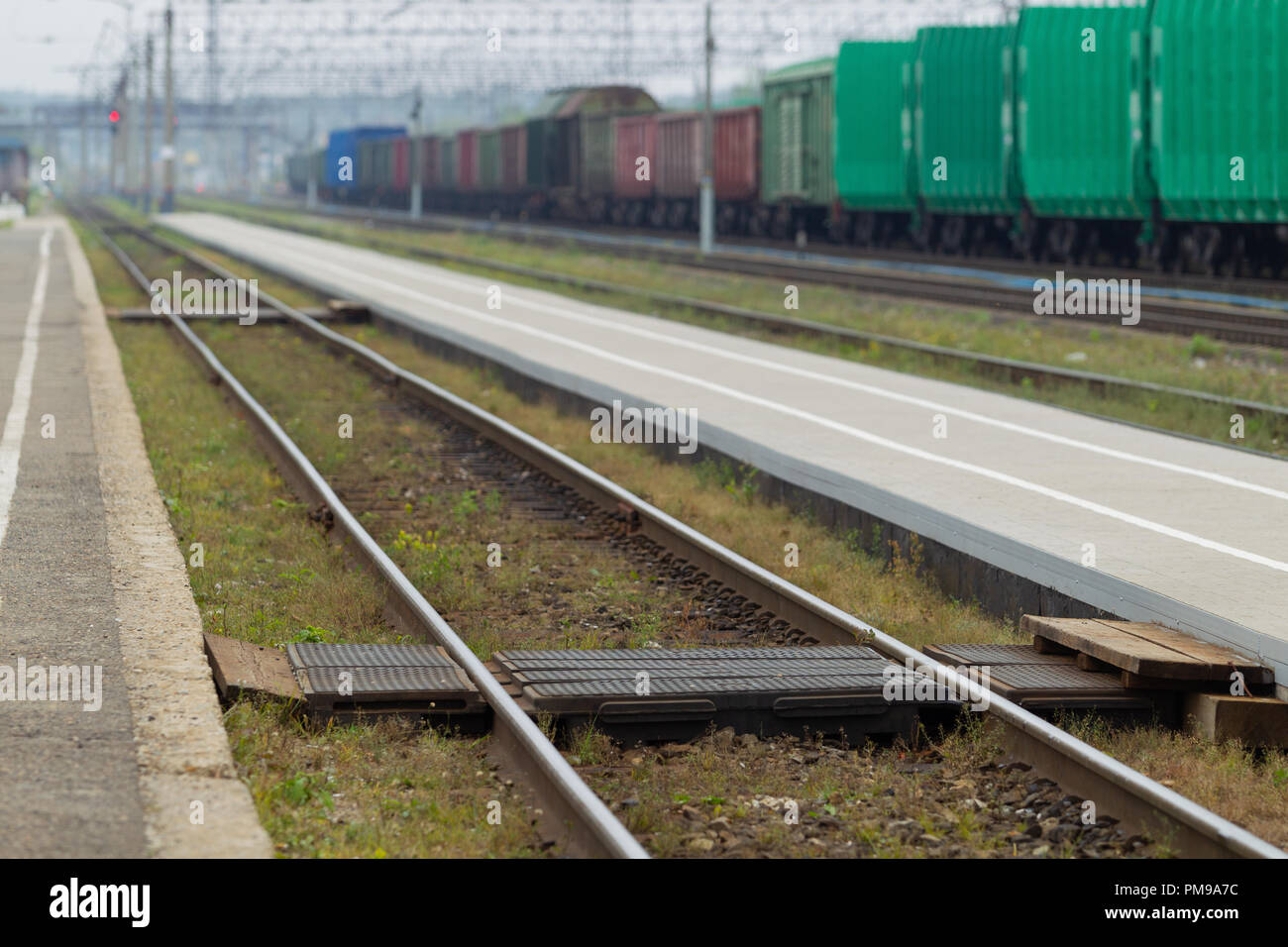 Attraversamento pedonale i binari ferroviari di trasporto hub, contro lo sfondo della piattaforma, rotaie e di treni merci. Luce naturale. Paesaggio Foto Stock
