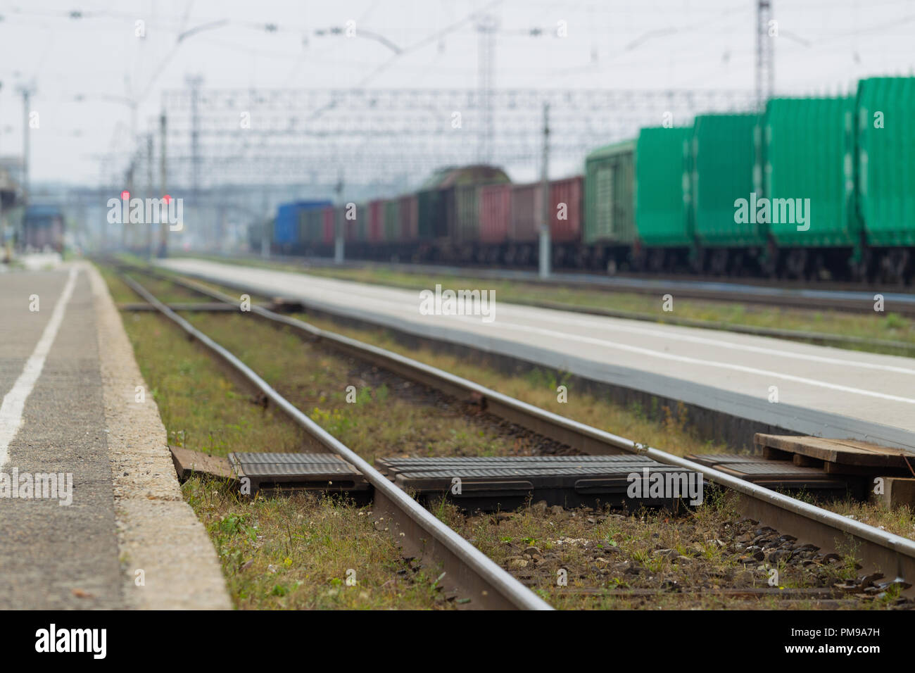 Attraversamento pedonale i binari ferroviari di trasporto hub, contro lo sfondo della piattaforma, rotaie e di treni merci. Luce naturale. Paesaggio Foto Stock