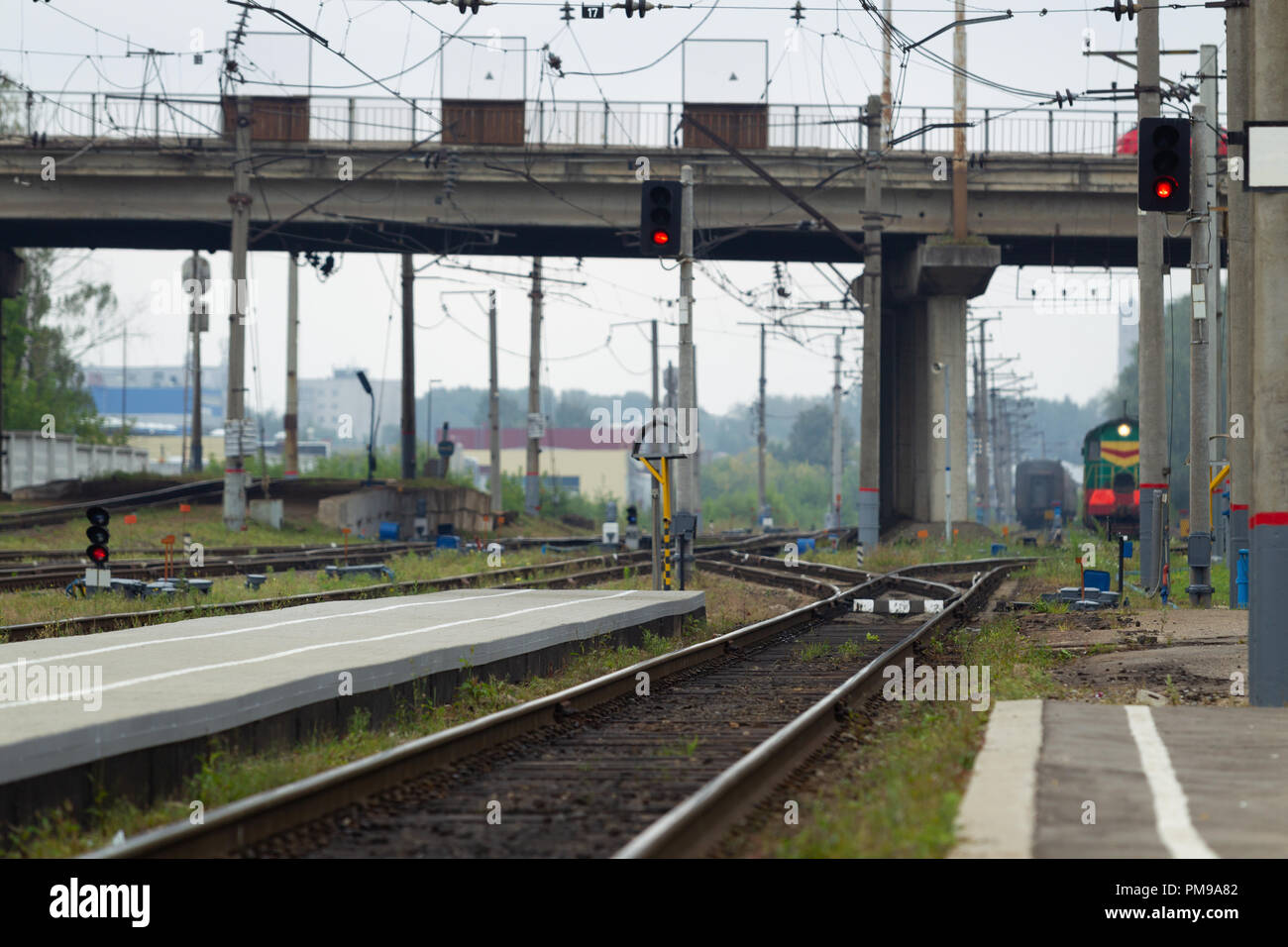 Il trasporto ferroviario giunzione con una piattaforma, rotaie e locomotori sullo sfondo del ponte autostradale e sullo skyline della città. Luce naturale Foto Stock