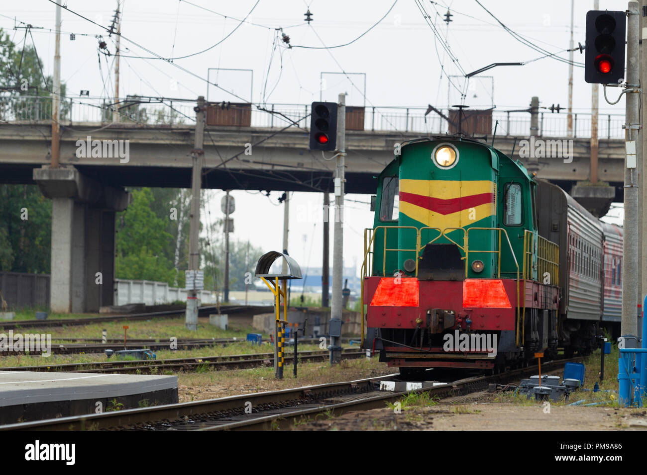 Locomotiva Diesel con le autovetture sulla piattaforma, Semaphore, rampa, nodo ferroviario e ponte autostradale. Paesaggio industriale. Luce naturale Foto Stock