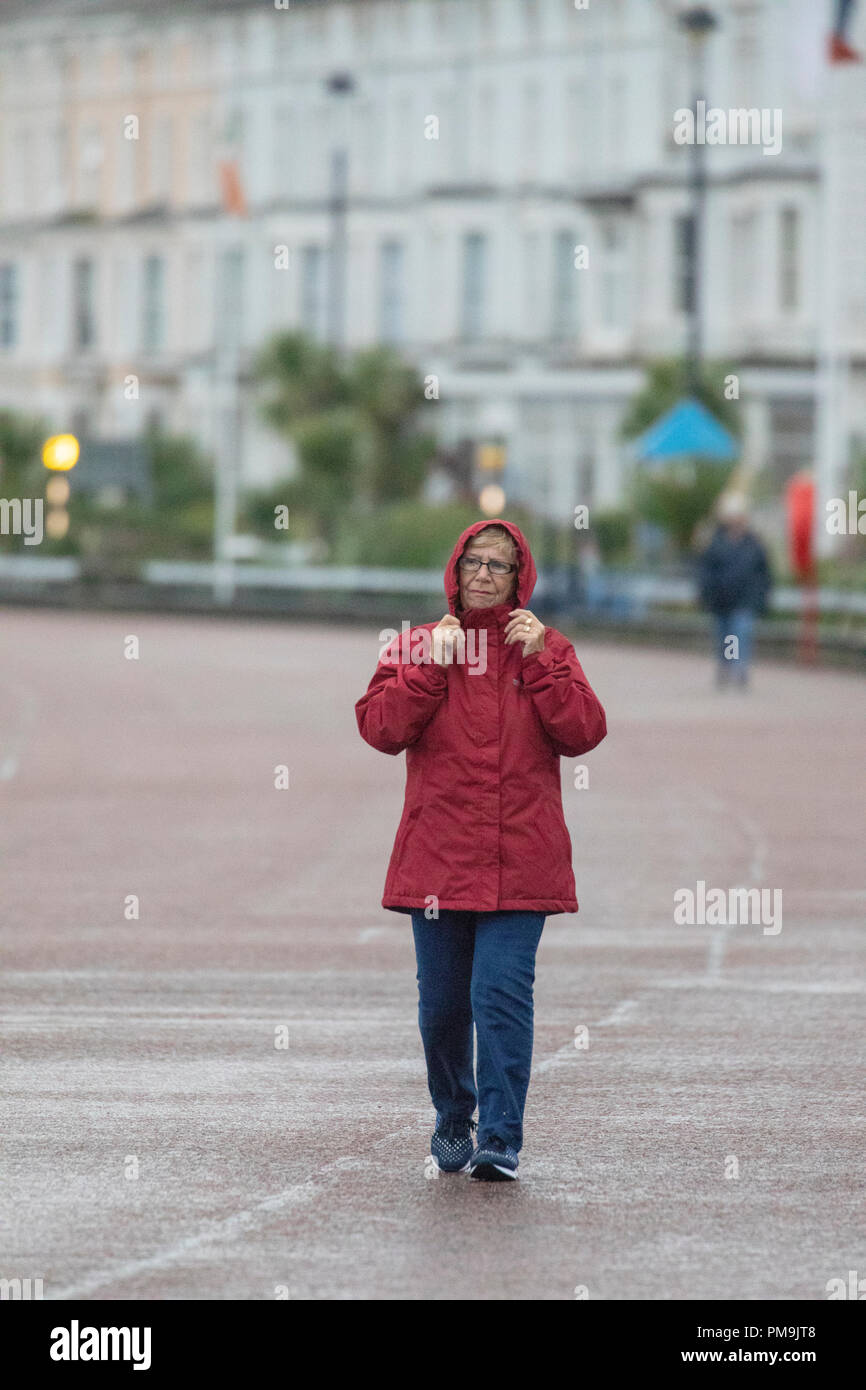 Il Galles del Nord, settembre 2018. Regno Unito: Meteo una Met Office avviso di colore giallo è in luogo di vento e tempeste costiere per il Galles del Nord come ex-uragano Helene rende approdo in tutta la regione. Una donna bretelle se stessa contro il vento meteo bagnato sulla passeggiata costiera di Llandudno, il Galles del Nord Foto Stock