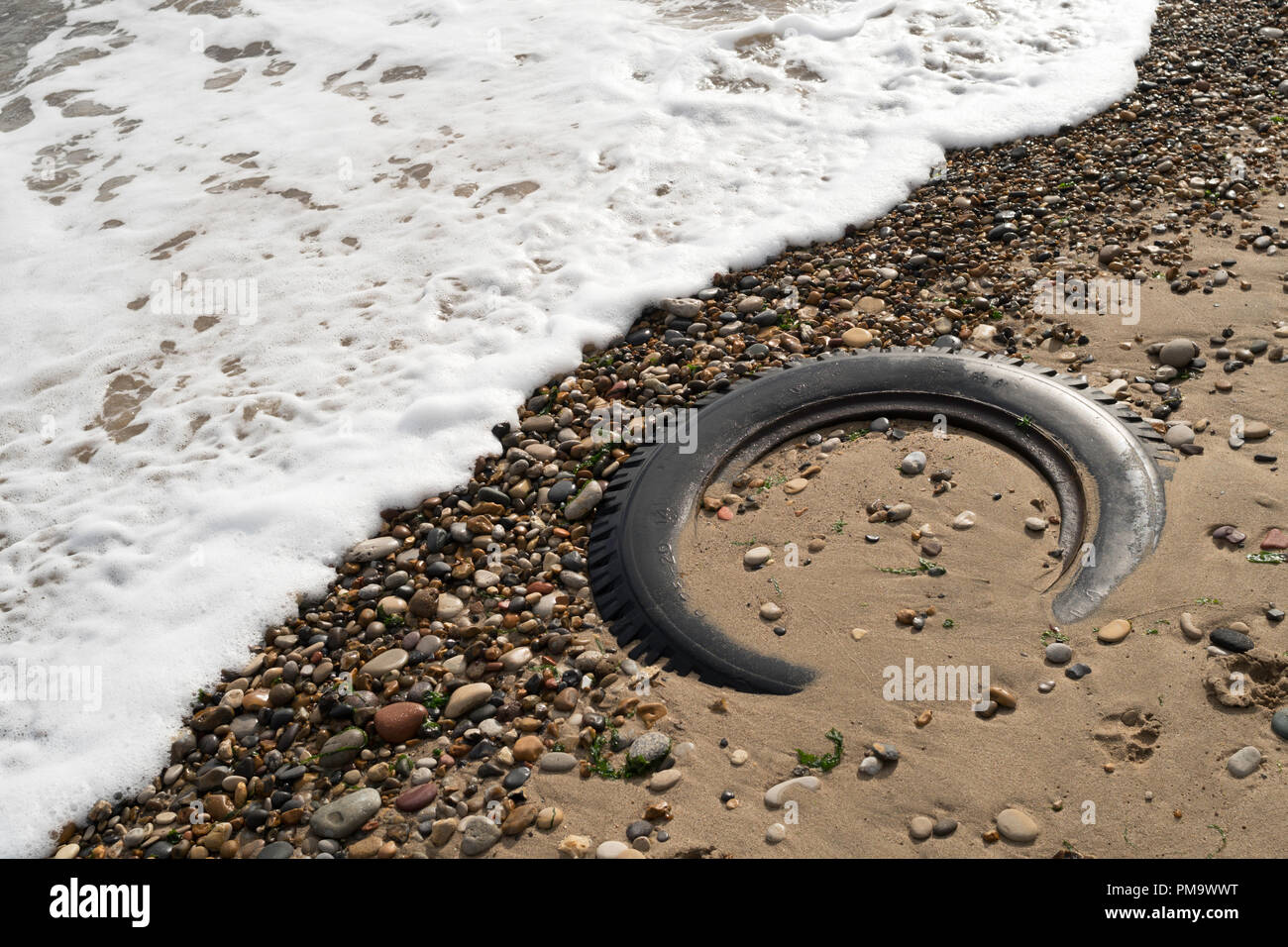 Vecchio veicolo ruota e pneumatico incorporato nella sabbia sulla spiaggia a Seaham, Co. Durham, England, Regno Unito Foto Stock