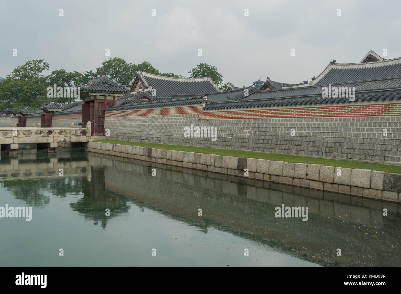 Una parete decorativa di mattoni e piastrelle, confinante con acqua, con una riflessione della parete, in Palazzo Gyeongbokgung, Seoul, Corea del Sud Foto Stock