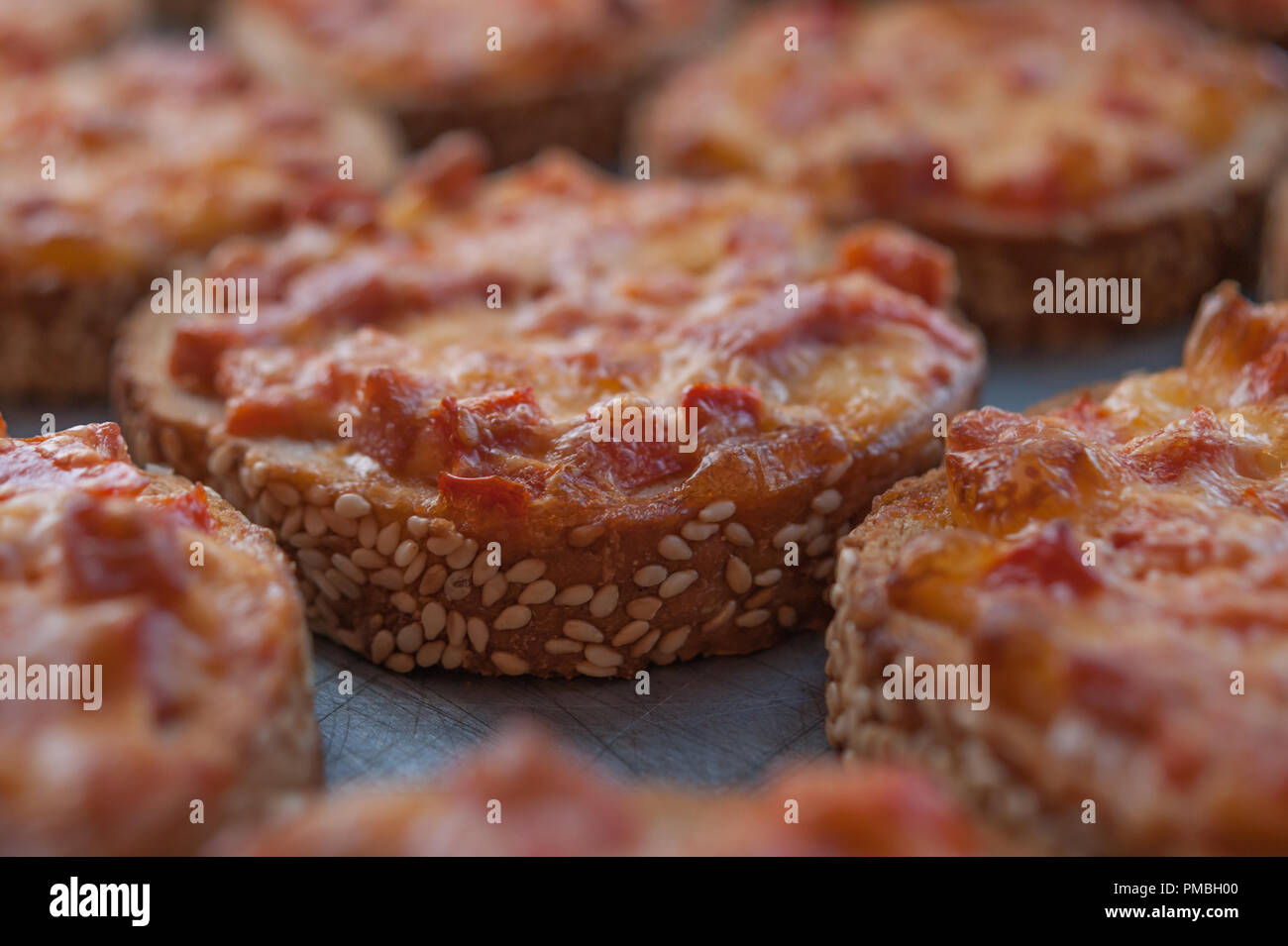 Facile rapido spuntino. Il SESAMO pane cotto con salame e formaggio sulla teglia da forno. Mini Pizza Foto Stock