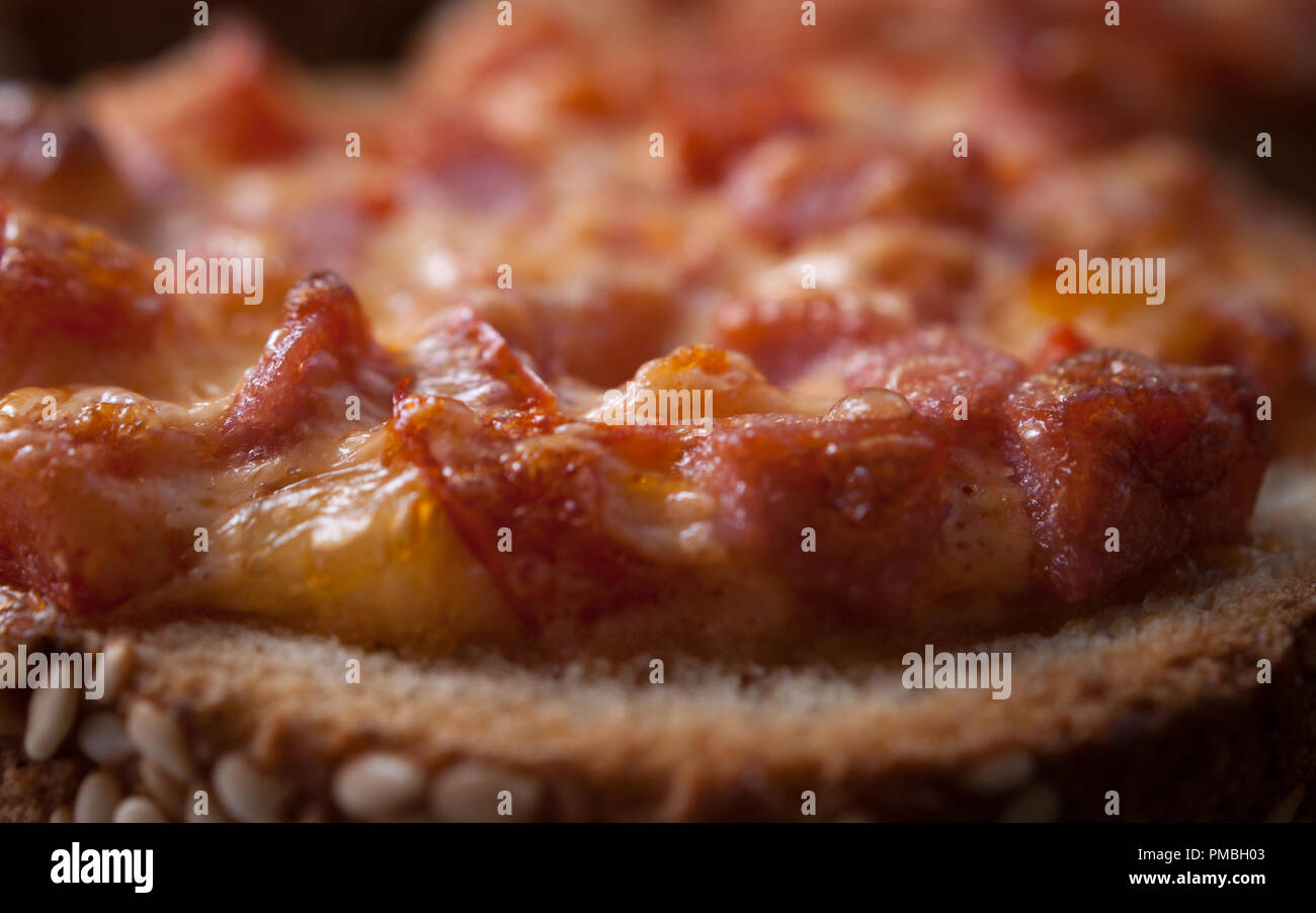 Facile rapido spuntino. Il SESAMO pane cotto con salame e formaggio sulla teglia da forno. Mini Pizza Foto Stock