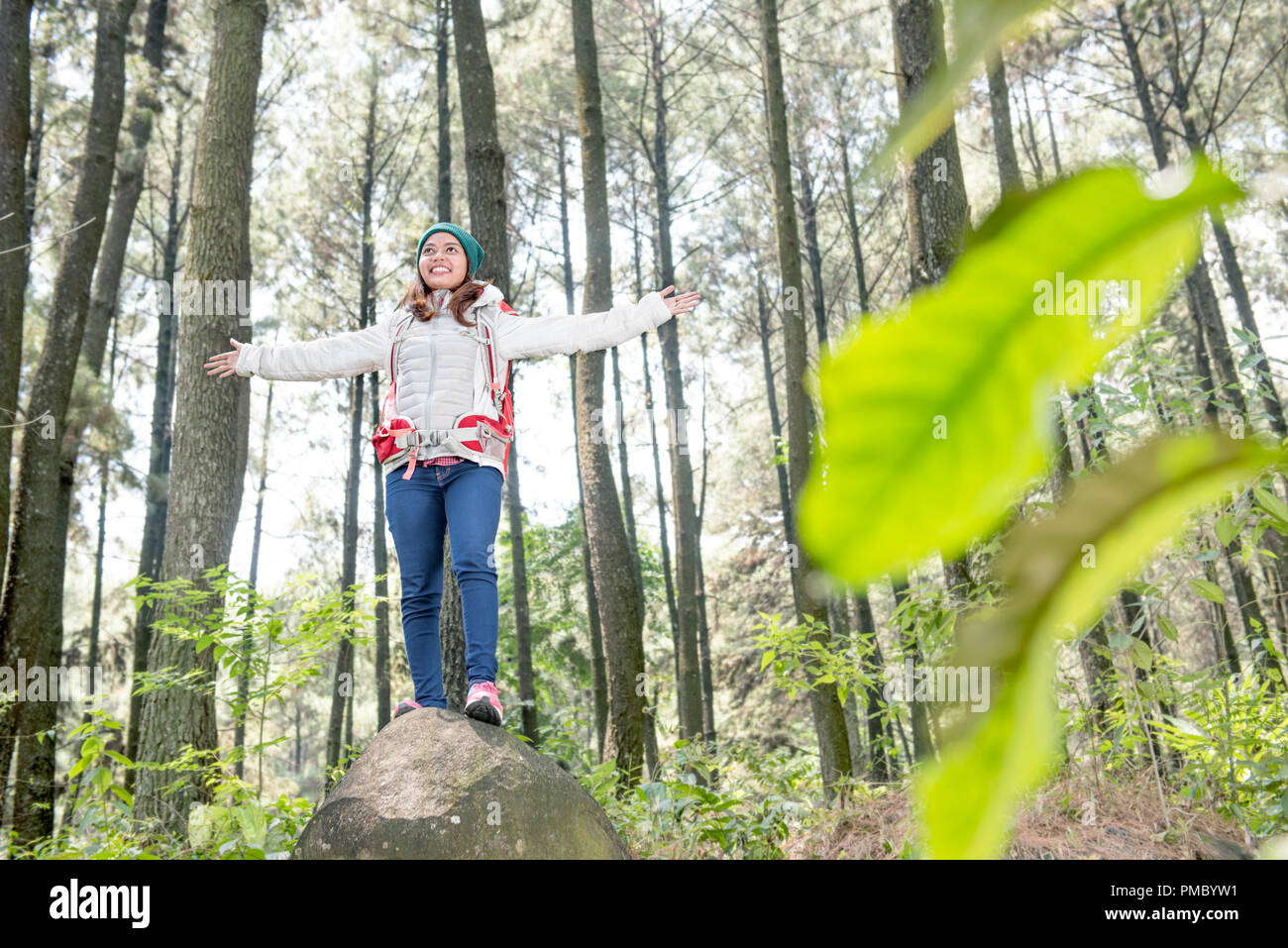 Felice viaggiatori asiatici donna in piedi con le braccia sollevate sulla foresta Foto Stock
