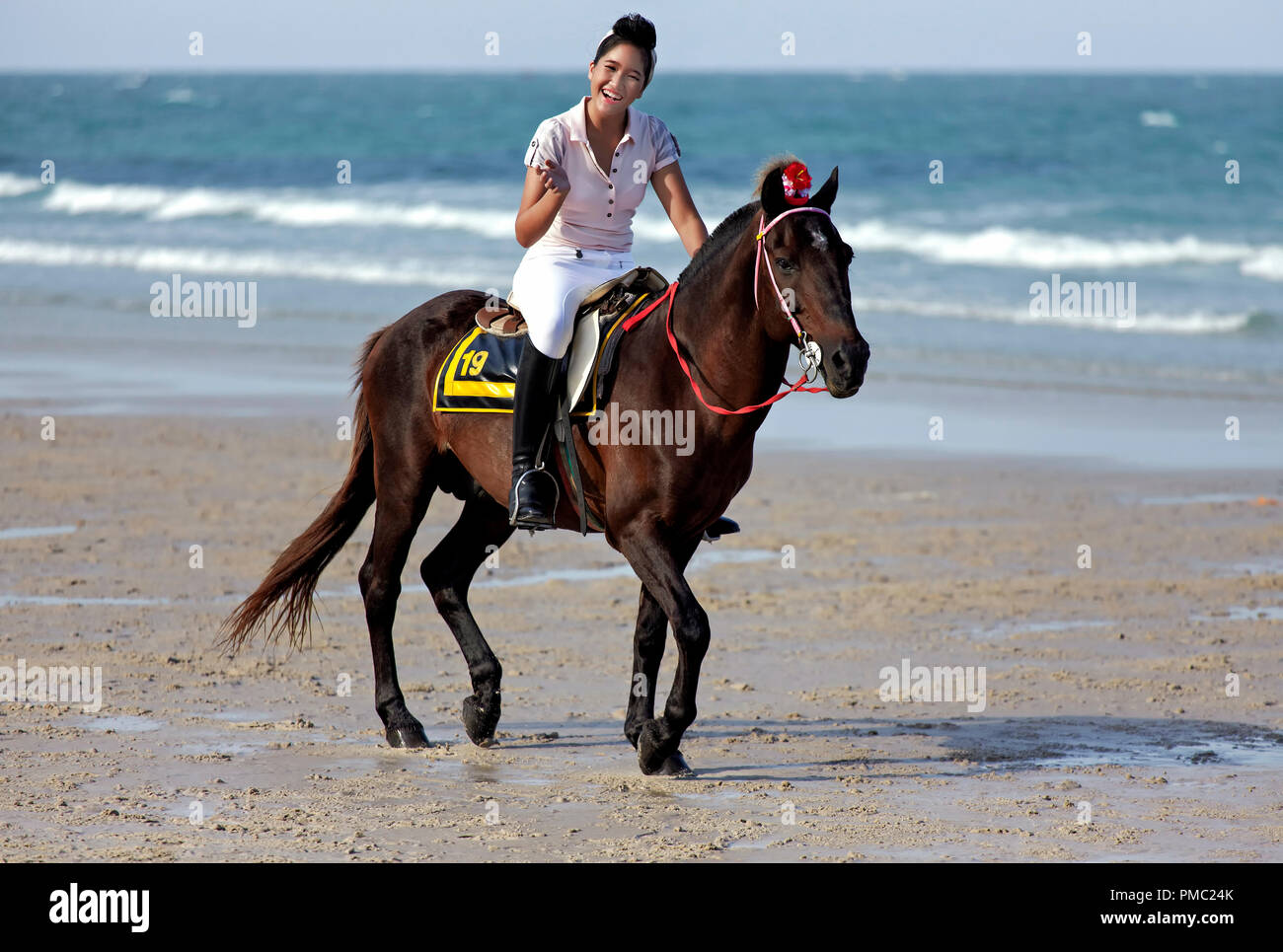 Donna equitazione spiaggia. Femmina ad un dressage di cavallo e ad un evento di moda equestre sulla spiaggia di Hua Hin Thailandia Foto Stock