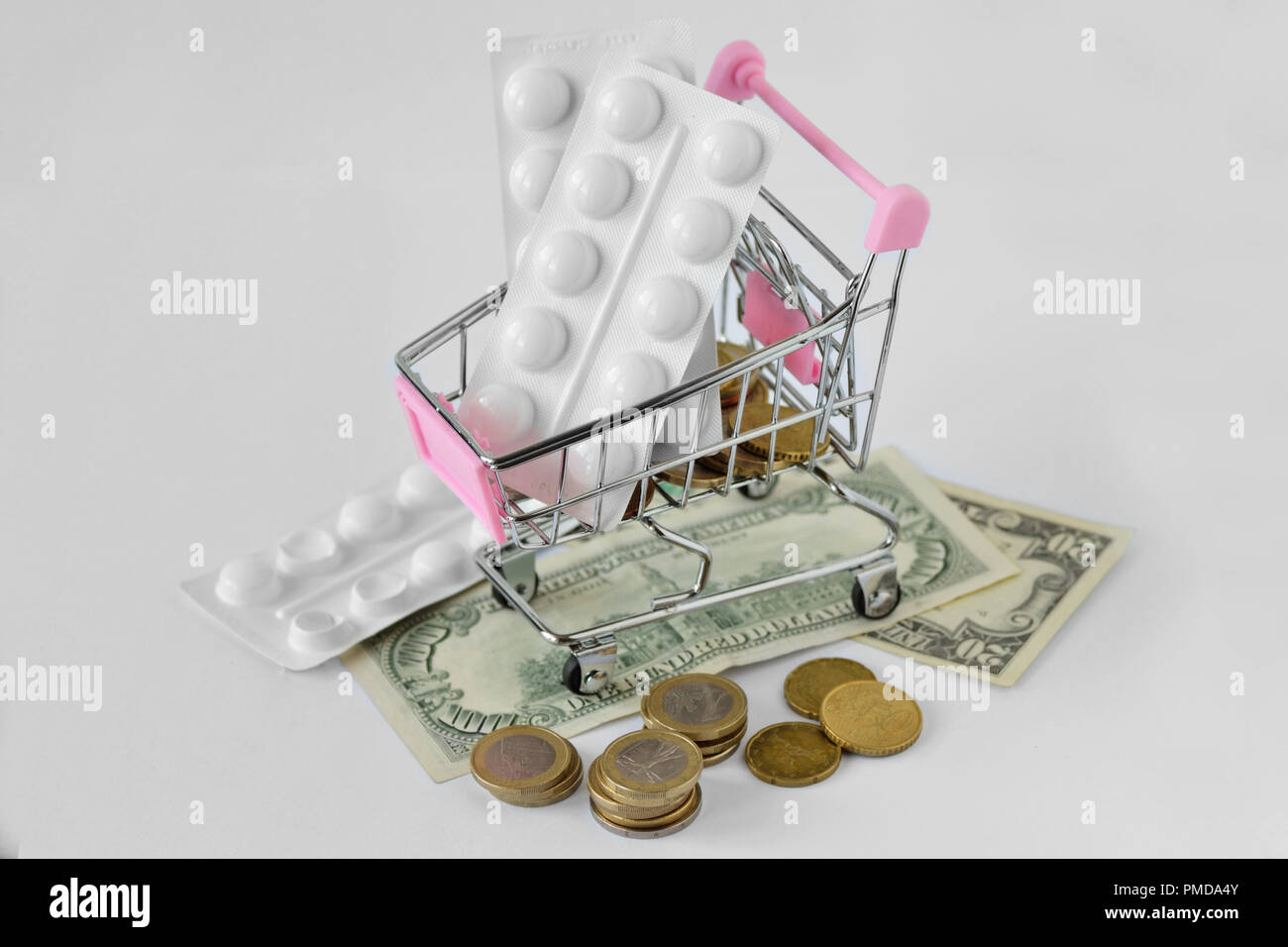 Pink carrello con pillole medicinali sul denaro - Pharmaceutical cost concept Foto Stock