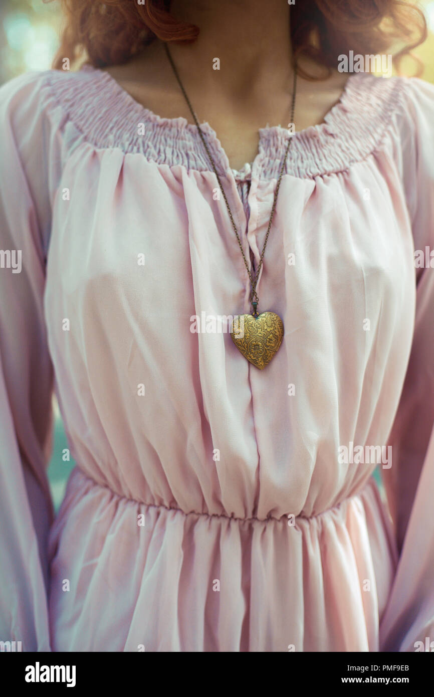 Auburn capelli donna in abito rosa con cuore collana pendente Foto Stock