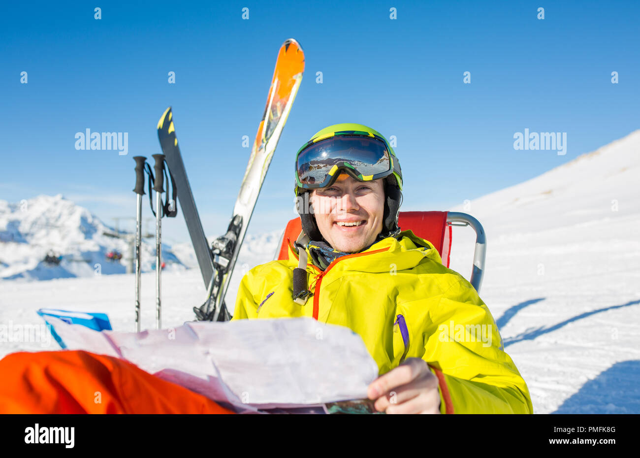 Foto di uomo sportivo nel casco seduto alla sedia in snowy resort Foto Stock