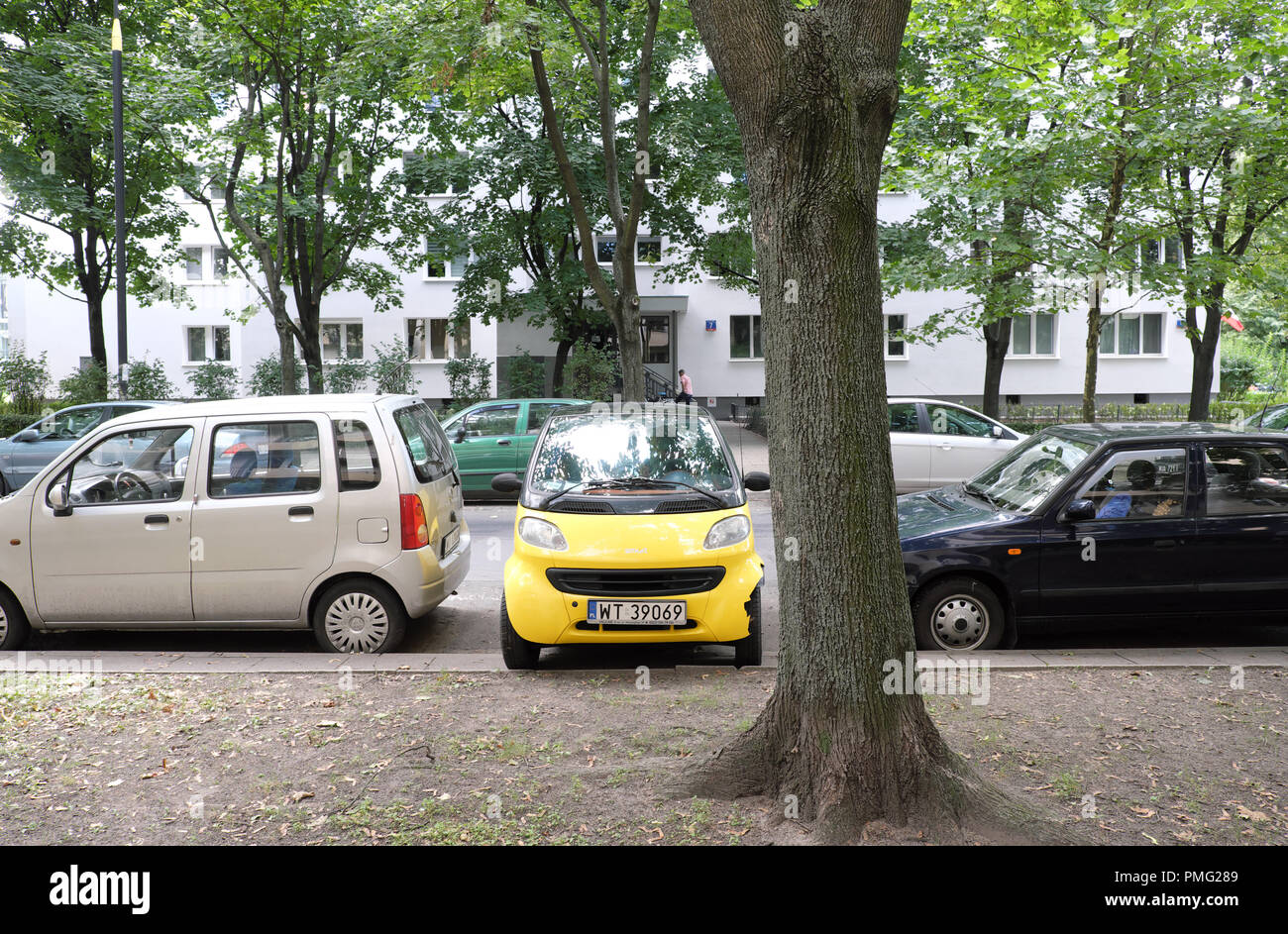 Varsavia Polonia un giallo Smart auto parcheggiate lateralmente in un piccolo spazio tra due vetture Foto Stock