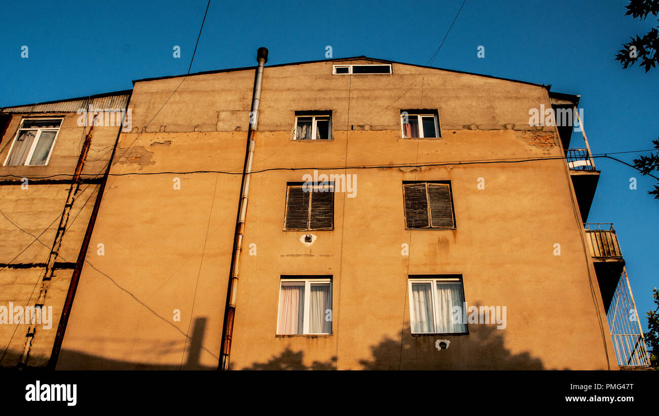 Il vecchio edificio di appartamenti a Tbilisi. Tramonto brilla sulla sua parete. Foto Stock
