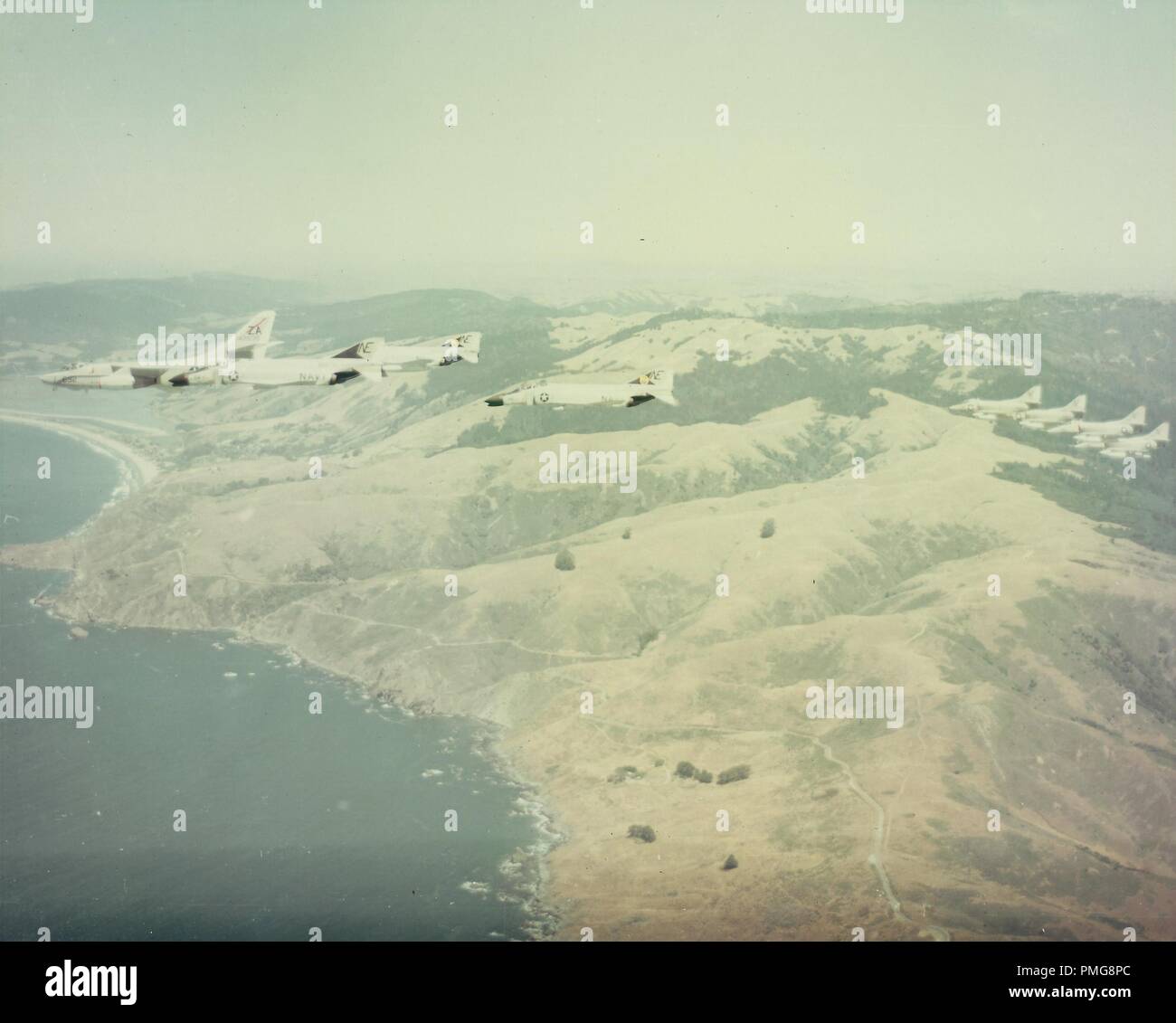 In bianco e nero la fotografia aerea mostra una squadra di 8 marina degli Stati Uniti, aeromobili McDonnell Douglas F-4 Phantom IIs, in volo, con le nuvole e le montagne in distanza, fotografato durante la Guerra del Vietnam, 1965. () Foto Stock