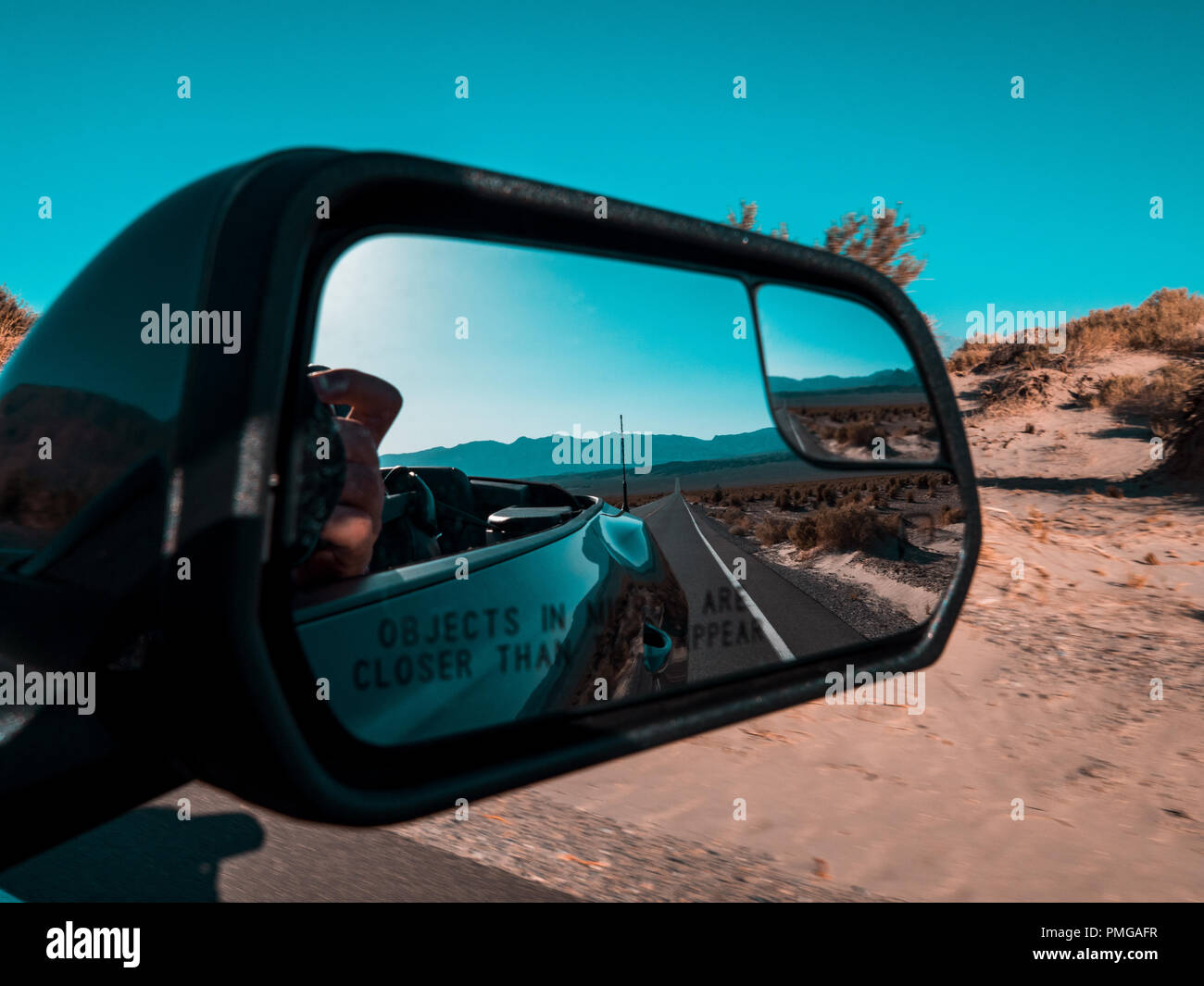 La guida lungo le strade solitarie della Death Valley con niente in siight ma su strada e dune di sabbia del deserto Foto Stock