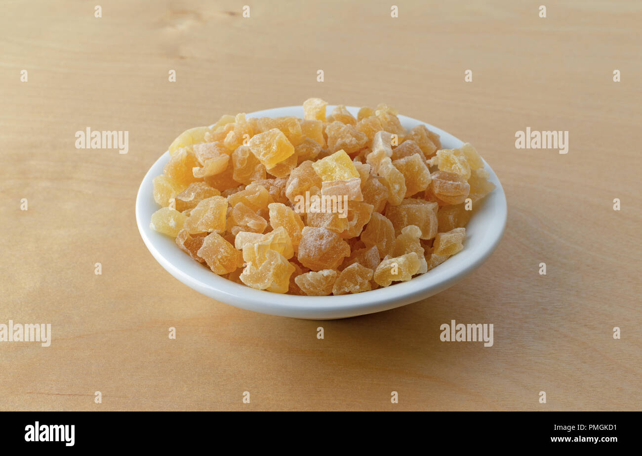 Una piccola ciotola riempita con secchi tagliati a dadini le pesche su un compensato di betulla tavolo illuminato con luce della finestra. Foto Stock