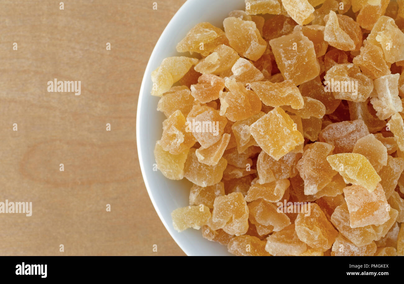 Top vista ravvicinata di una piccola ciotola riempita con secchi tagliati a dadini le pesche su un compensato di betulla tavolo illuminato con luce della finestra. Foto Stock