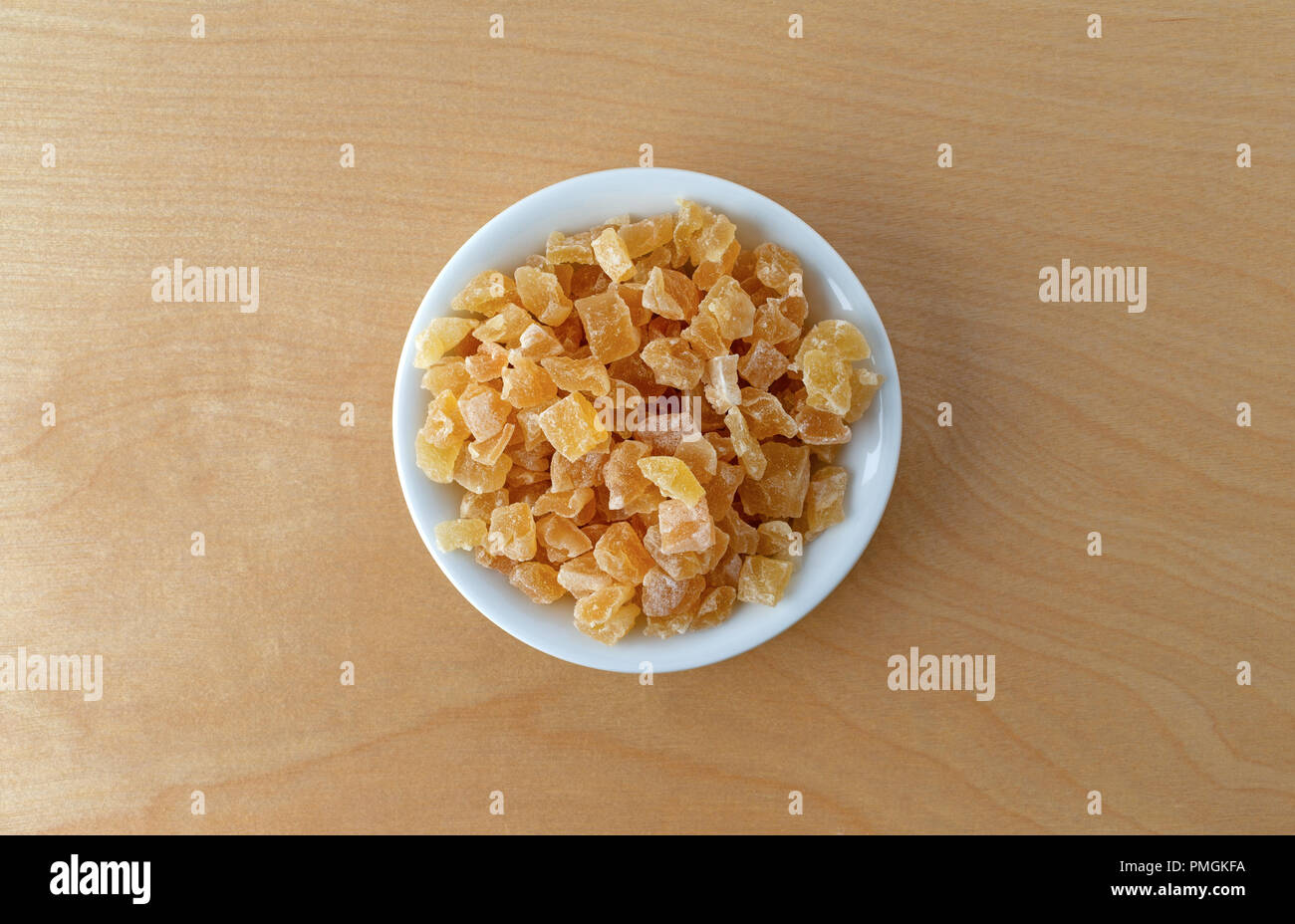 Vista dall'alto di una piccola ciotola riempita con secchi tagliati a dadini le pesche su un compensato di betulla tavolo illuminato con luce della finestra. Foto Stock