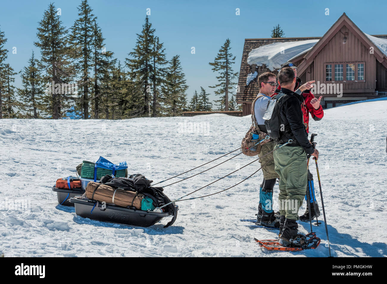 Di Crater Lake, Oregon, Stati Uniti d'America - 22 Marzo 2014: snow shoeing hilkers ottenere pronto per la testa fuori per il campeggio, tirando il loro ingranaggio dietro in slittini, presso il cratere del lago Foto Stock