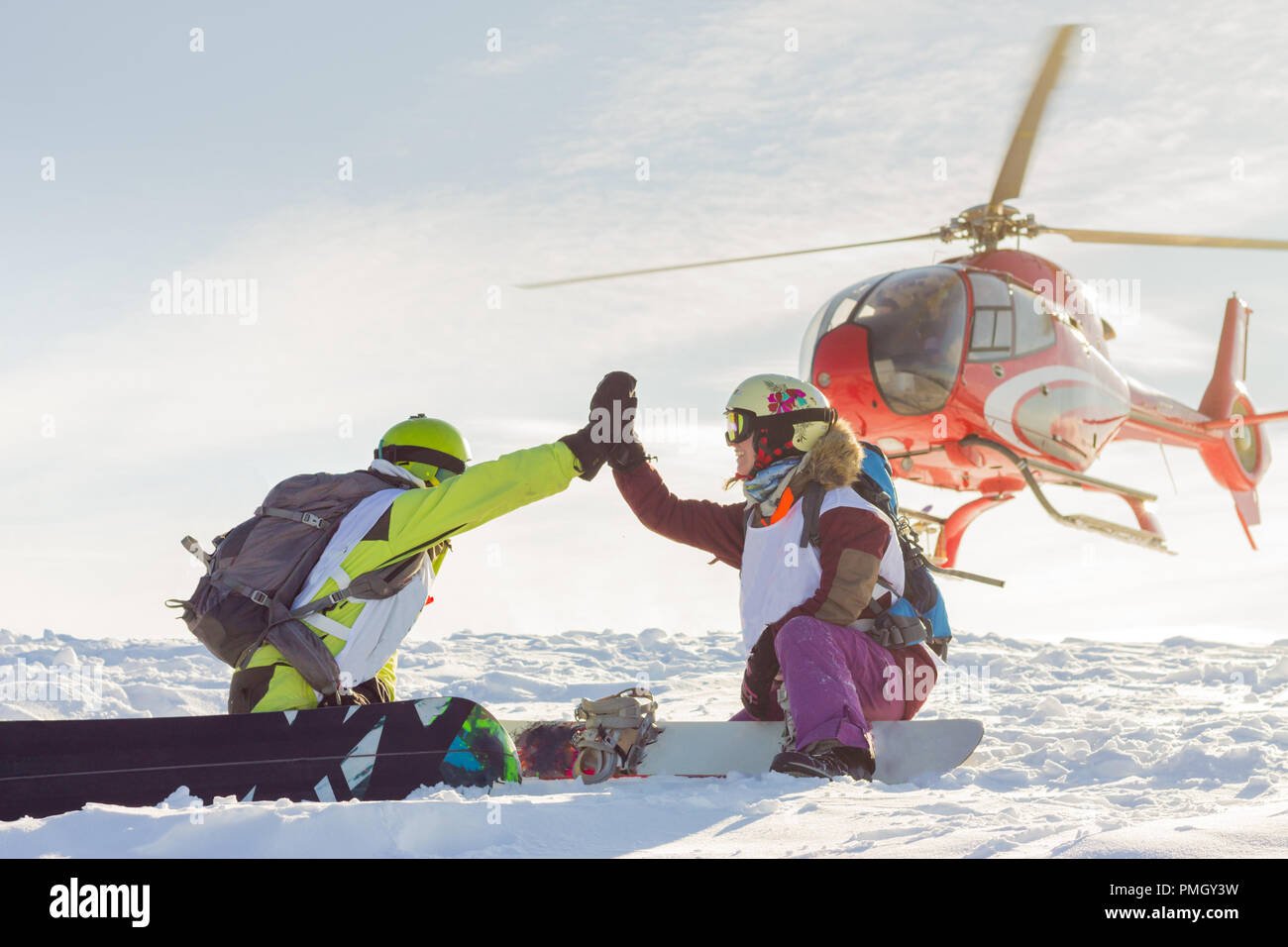 Coppia di freerider di snowboarders dare cinque quando l'elicottero atterra. Foto Stock