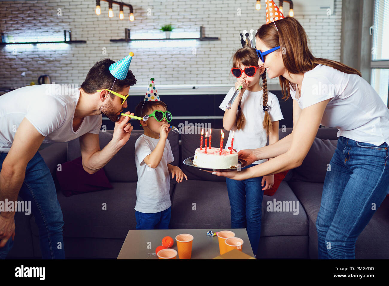 Una famiglia felice con una candela torta celebra un compleanno Foto Stock