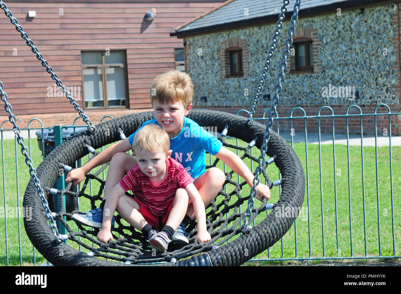 Due bambini piccoli su una oscillazione circolare in un parco giochi Foto Stock