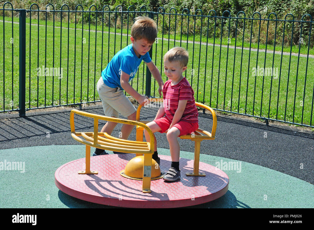 Due piccoli ragazzi giocano su una rotatoria in un parco giochi. Foto Stock