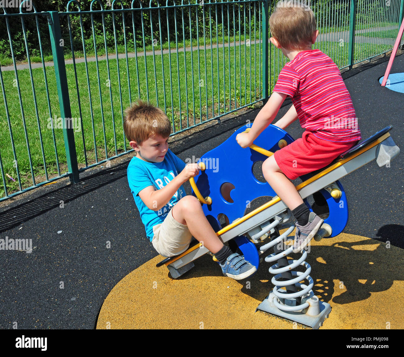 Due piccoli ragazzi giocare su un altalena in un parco giochi. Foto Stock