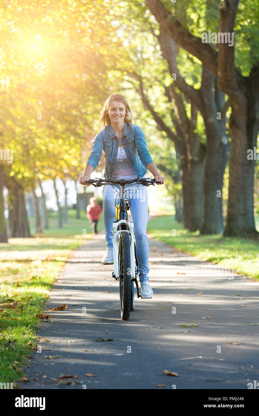 Giovane donna in bicicletta nel parco d'autunno. Godendo mentre escursioni in bicicletta nella natura durante la giornata autunnale. Foto Stock