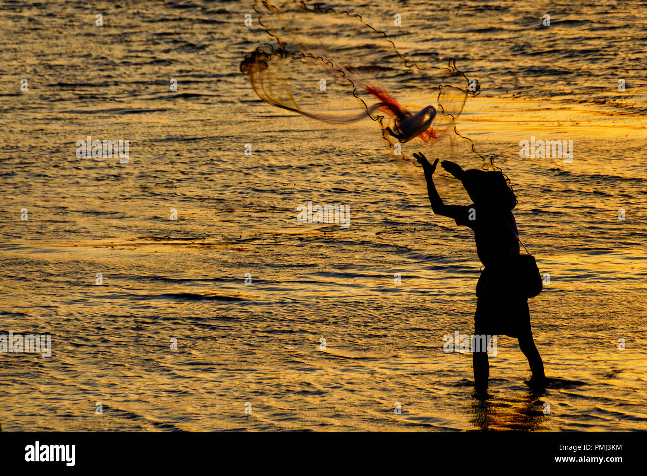 Silhouette di un pescatore di fusione il suo netto, Sanur, Bali, Indonesia Foto Stock