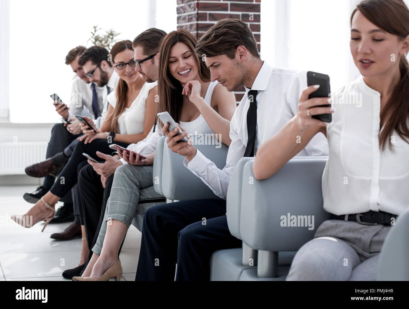 Un gruppo di dipendenti che utilizzano la loro gadget seduta nel corridoio di office Foto Stock