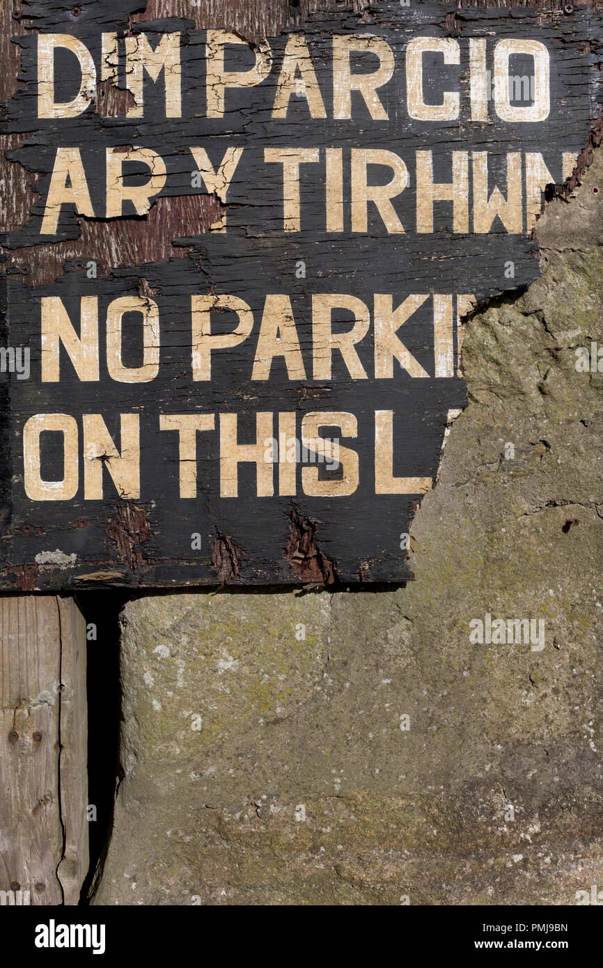 La rottura di un peeling e segno attenzione sia in lingua inglese e gallese, di parcheggio non il 13 settembre 2018, in Barmouth, Gwynedd, Galles. Foto Stock