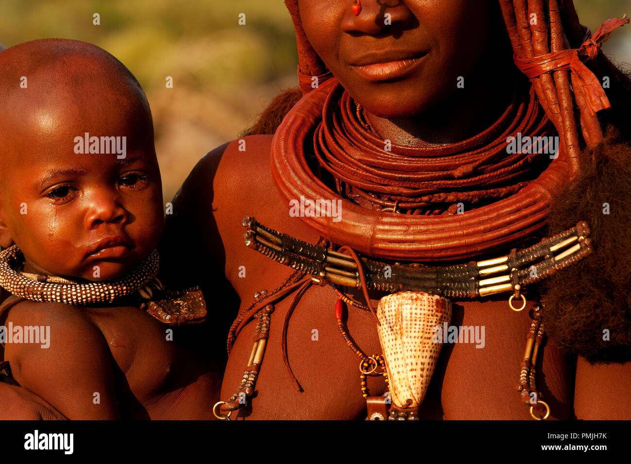Himba madre con i tradizionali ornamenti con il piccolo bambino, Epupa Falls, Namibia Foto Stock